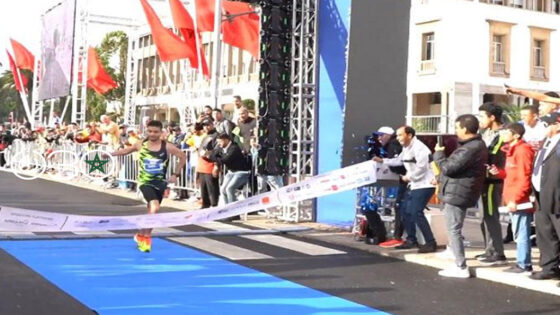 حفيظ رزقي وكلثوم بوعسرية يرفعان كأس السباق الدولي 10 كلم الدار البيضاء مع 4100 عداء خلفهما على الشارع الرئيسي